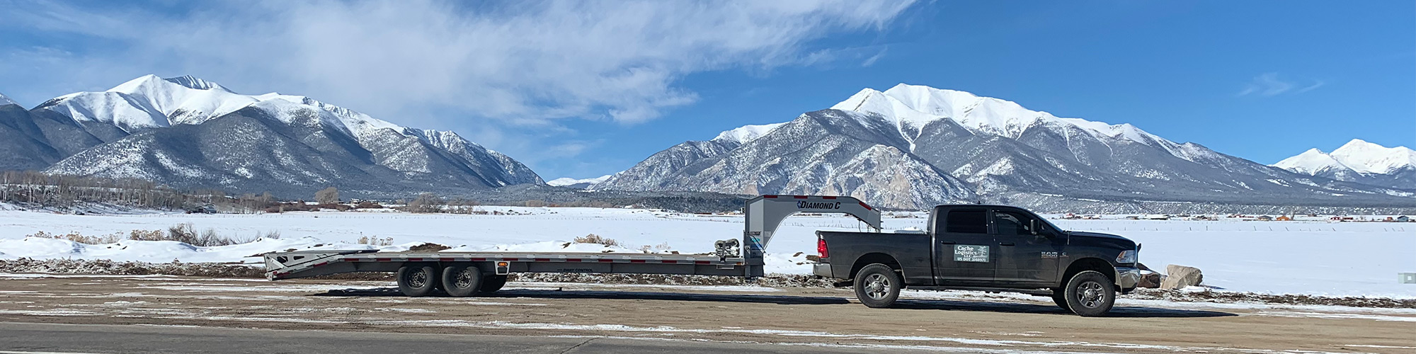Scenic photo of a gooseneck trailer being pulled by a truck with mountains behind