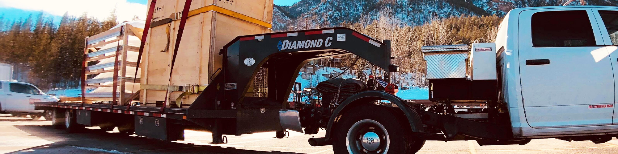 A Diamond C gooseneck FMAX trailer being pulled by a truck hauling cargo down the road.