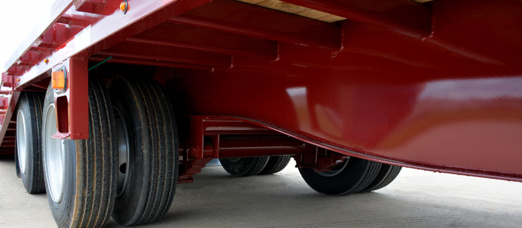 underside view of a trailer axle, suspension system, wheels, and tires.