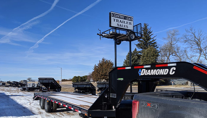 Country Load Trailers Sign with a Diamond C trailer in front
